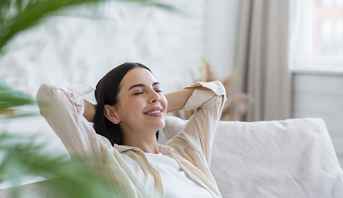 A smiling young woman leaning back on a sofa
