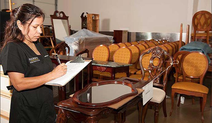 A restoration expert performing a detailed inventory of salvaged furniture items
