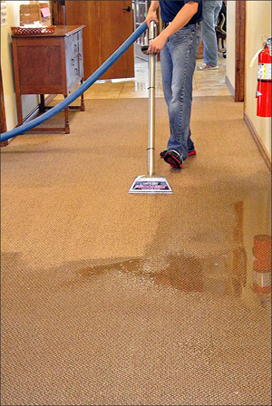 Extracting water from carpet Technician extracting water from commercial property