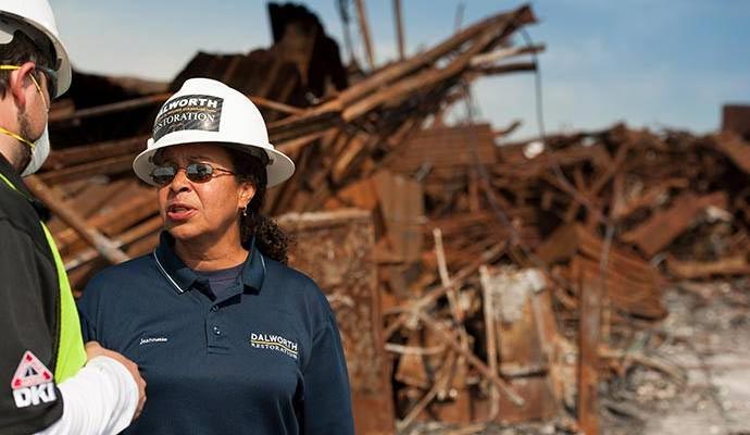 Two professionals assessing disaster damage in front of a damaged property