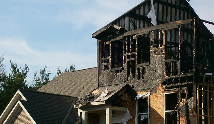 Fire damaged house A severely burnt house with charred walls and roof