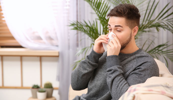 Young man blowing nose with tissue