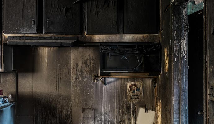 Fire-damaged kitchen showing charred cabinets and burned interior