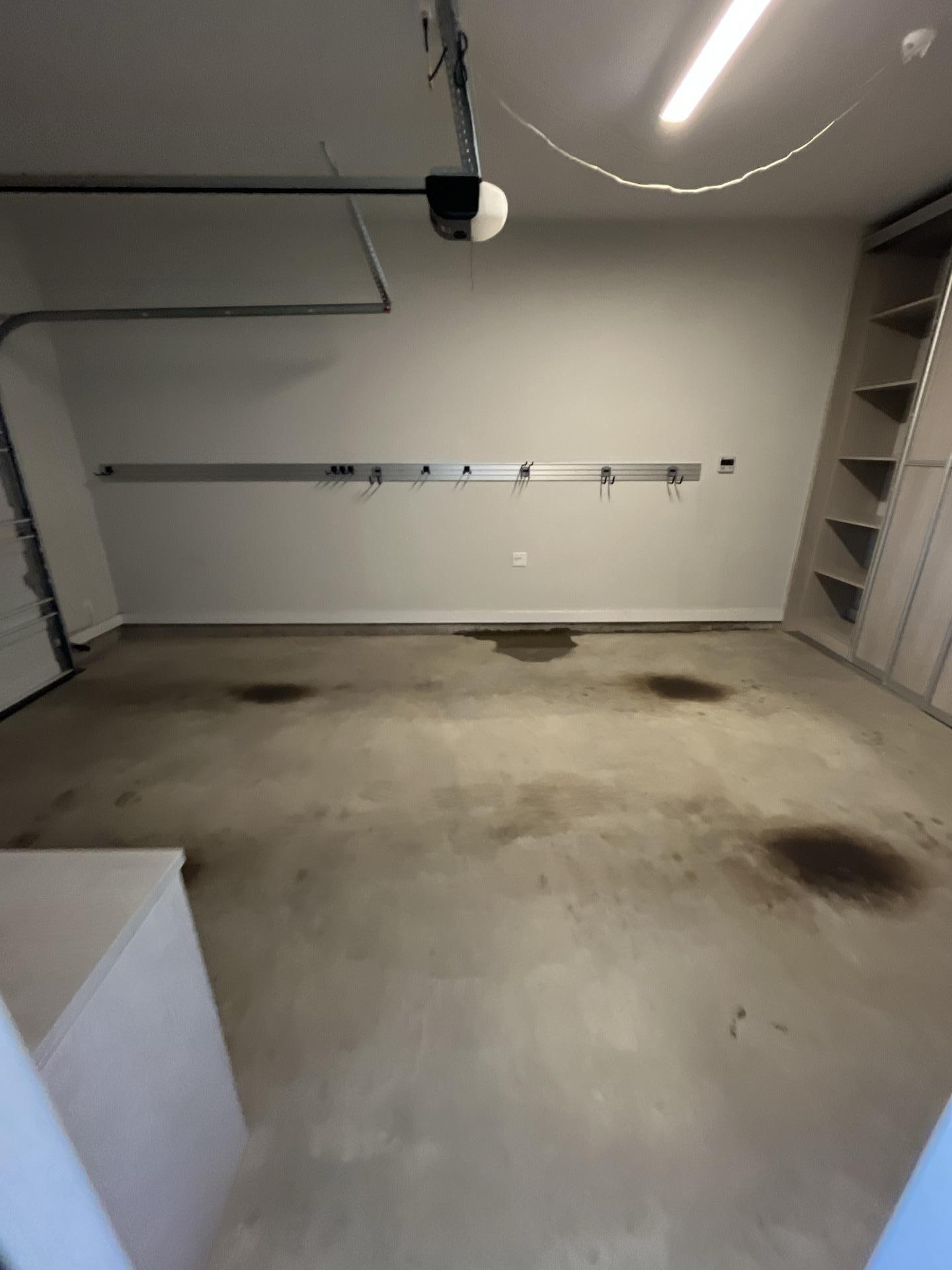 Close-up view of water intrusion and stains on a concrete garage floor requiring immediate structural drying and water damage restoration service to prevent mold.