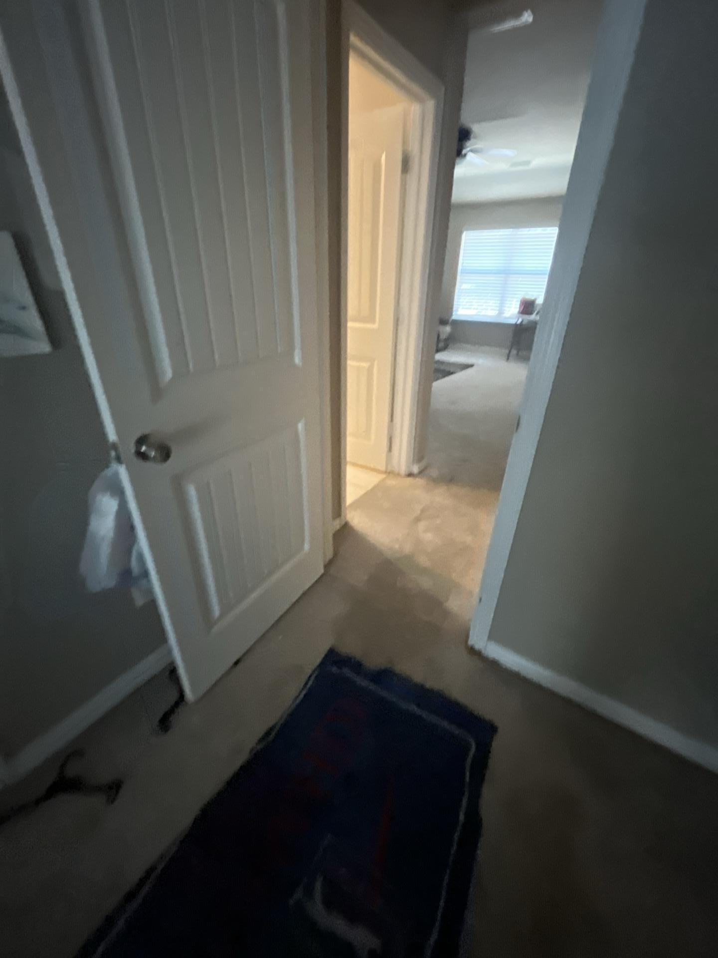 Checking the spread of water damage in the upstairs hallway leading to the affected bedroom. Comprehensive water mitigation requires inspection of all adjacent areas to ensure thorough structural drying and complete property restoration services.