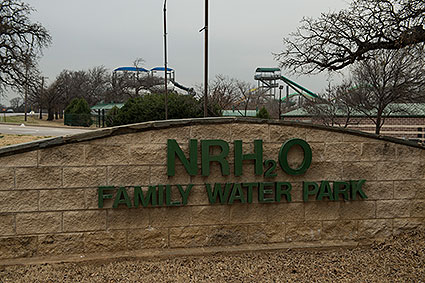 NRH2O is a family water park in North Richland Hills, TX featuring water slides, a wave pool, a lazy river, and various play and swimming areas for all ages.