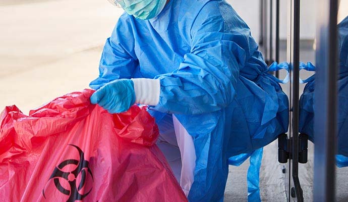 Technician handling red biohazard waste bag Technician handling red biohazard waste bag
