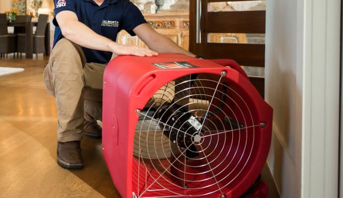Technician setting up a air mover fan to dry water damage