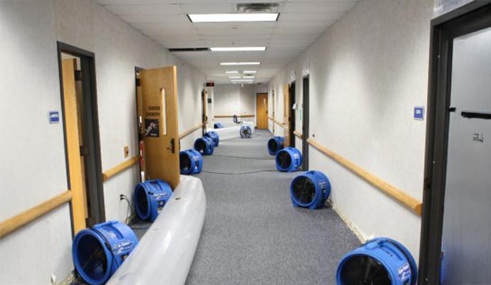 Water damage restoration setup in a hotel hallway with drying equipment